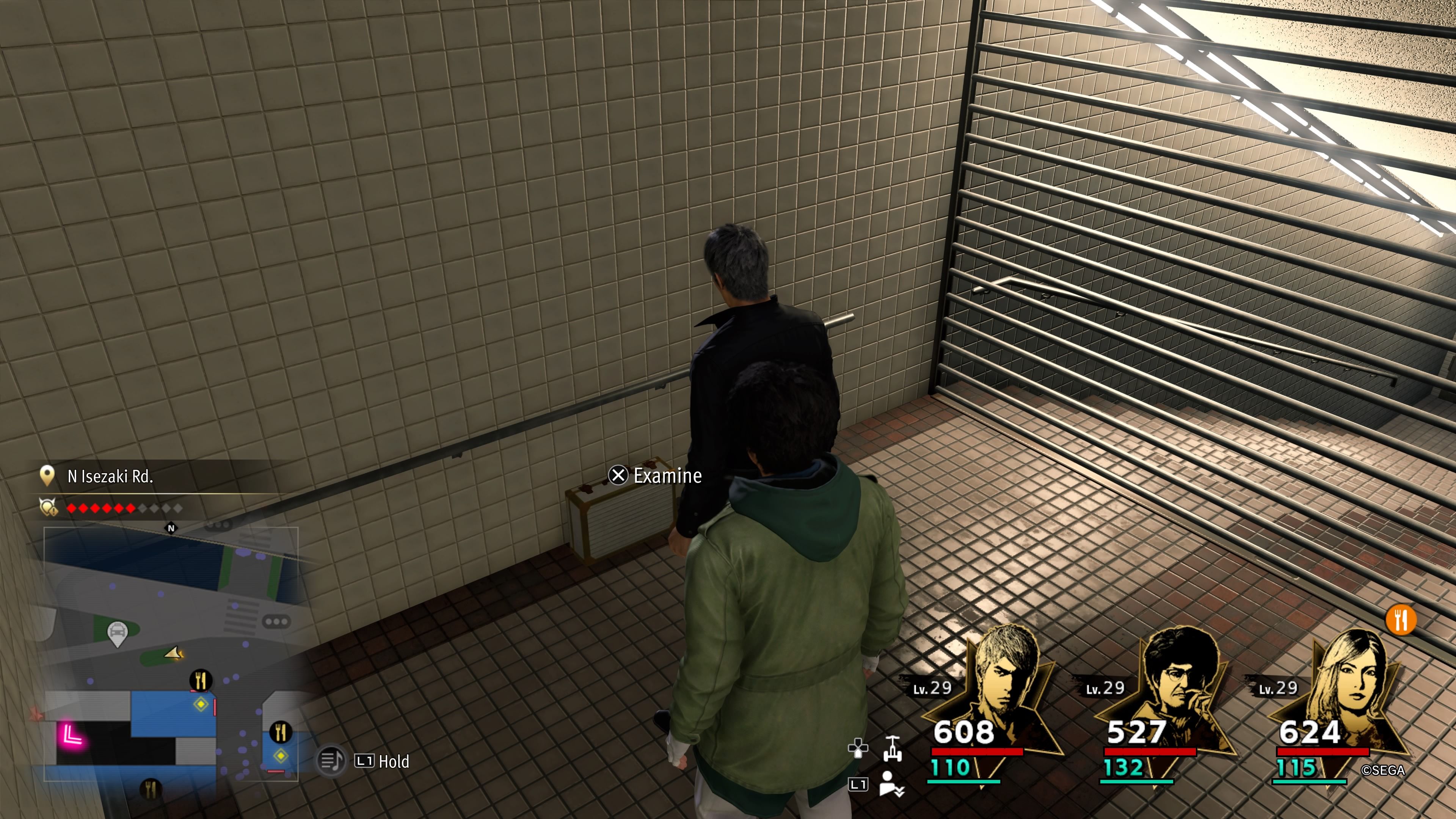 Kiryu de pie frente a una caja del tesoro al pie de una escalera cerca de una entrada cerrada del metro en Like A Dragon: Infinite Wealth.