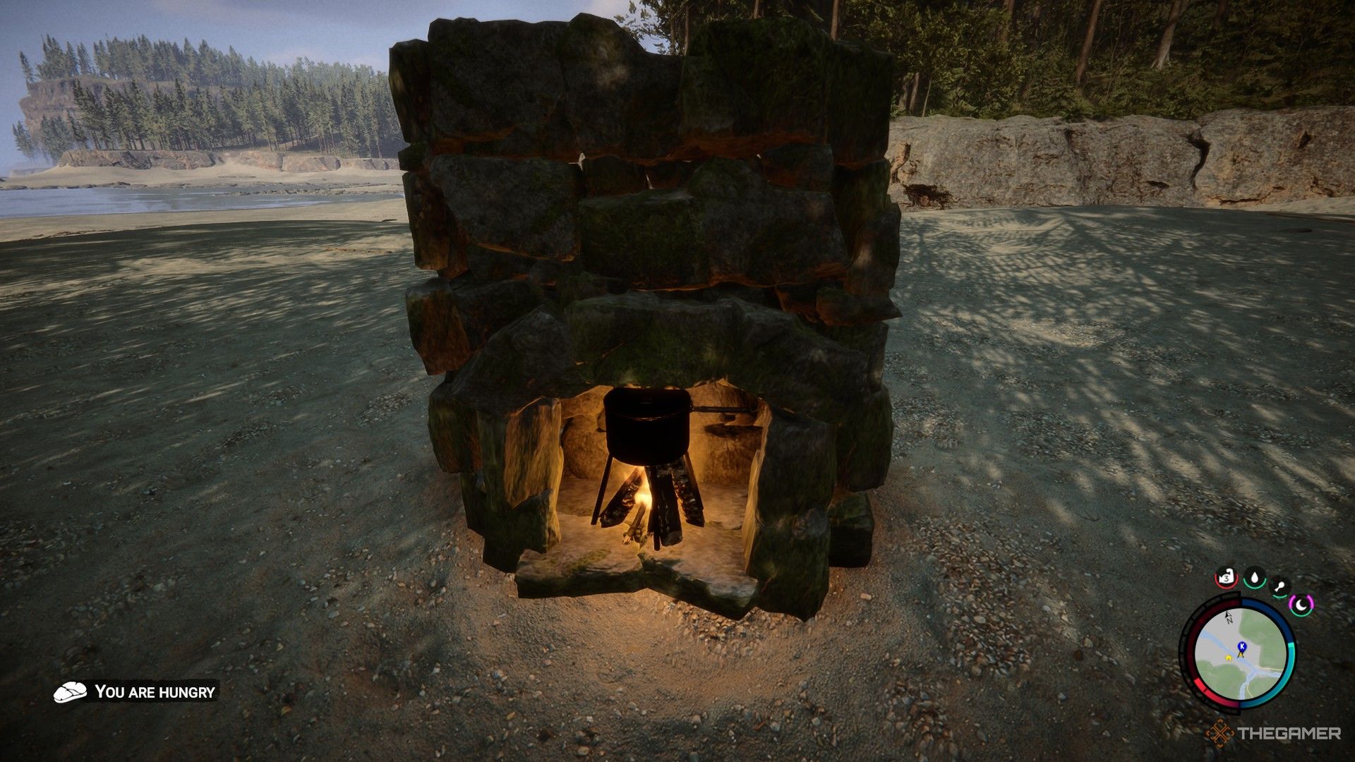 Una captura de pantalla de Sons of the Forest que muestra un fuego con una olla encima de una chimenea de piedra descansando en una playa.