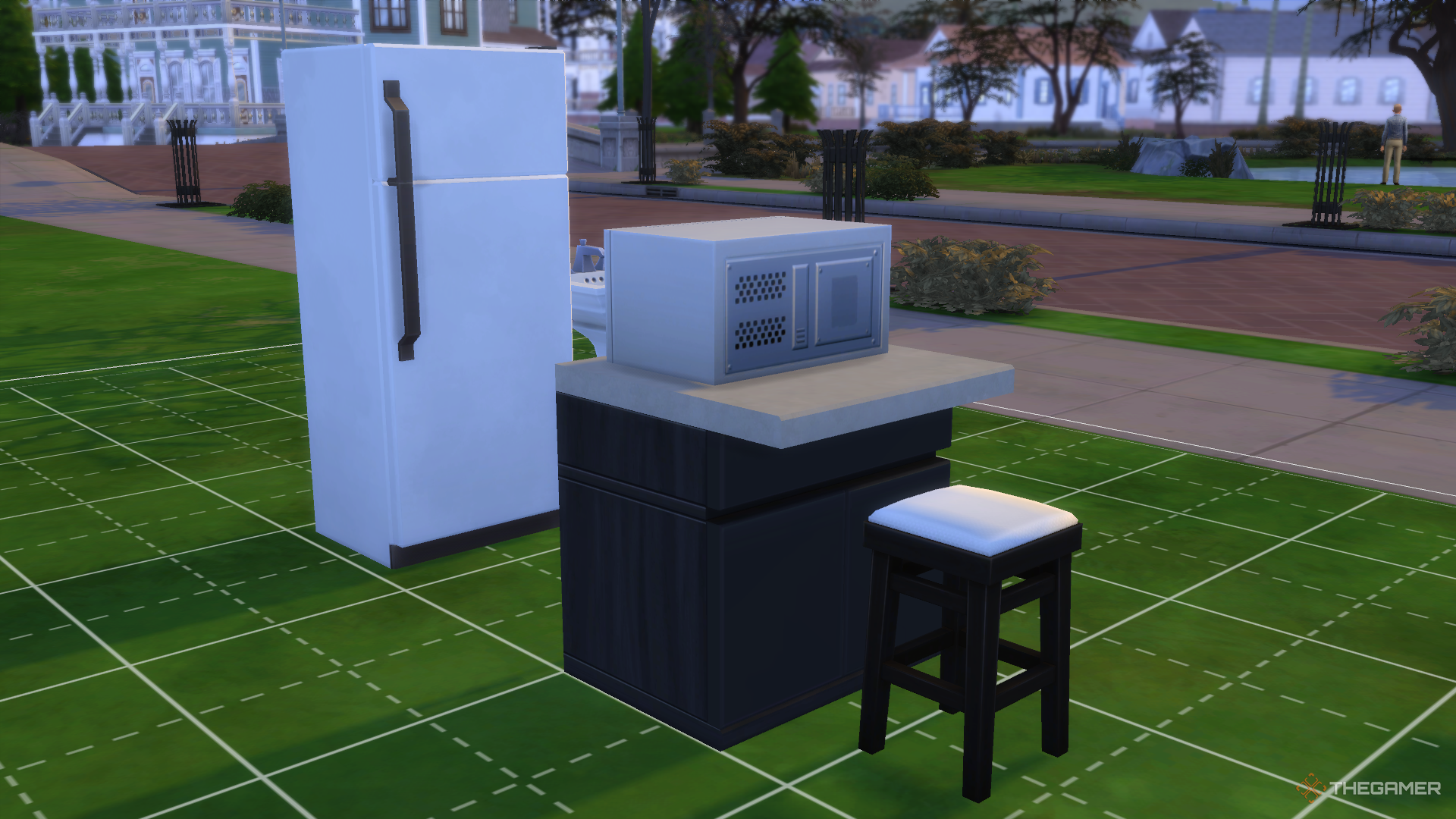 Muebles y electrodomésticos de cocina dispuestos en el jardín delantero junto a la calle en Los Sims 4.