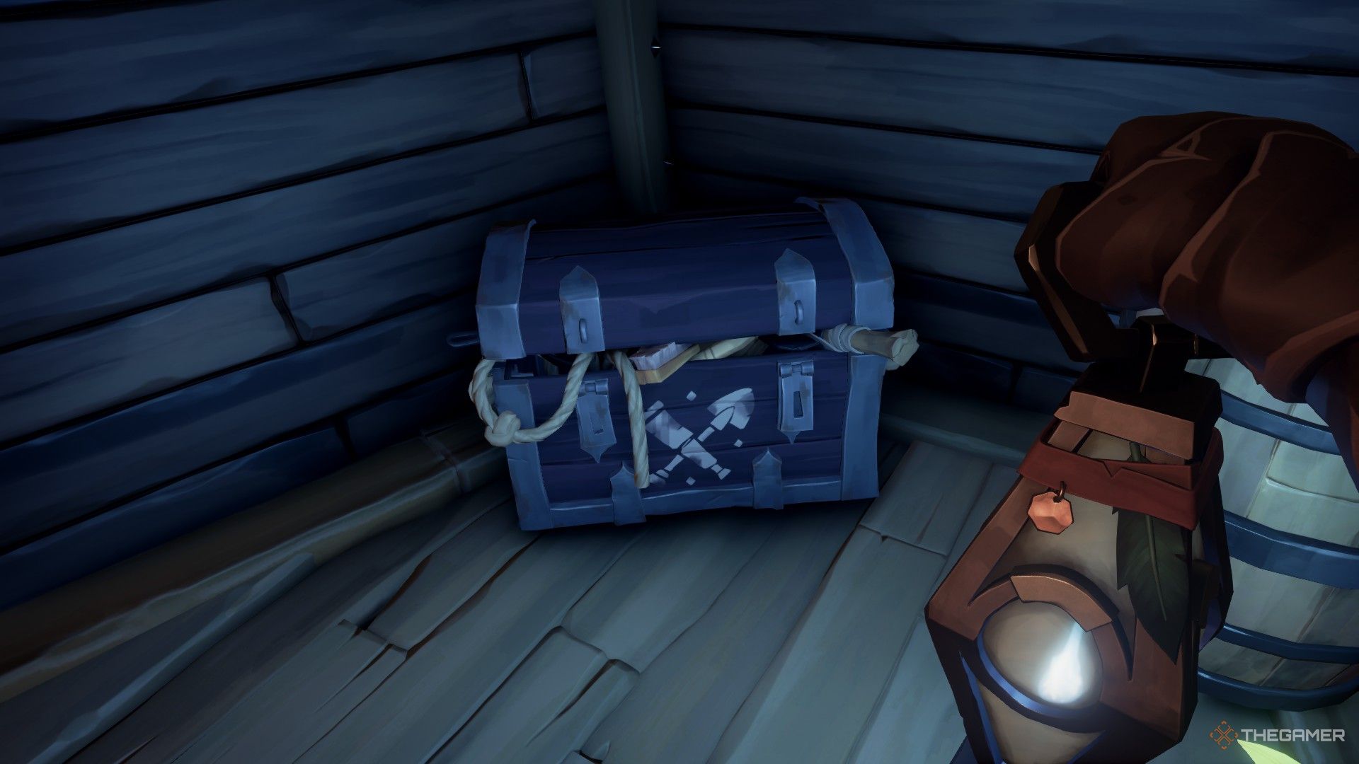 Una captura de pantalla de Sea of ​​Thieves que muestra el cofre de equipo debajo de la cubierta de un barco, visible con una pala y un telescopio.