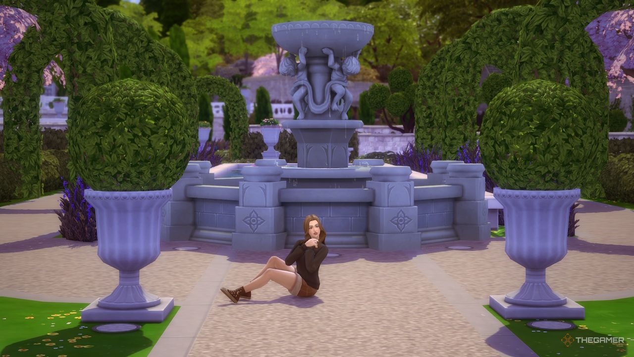 Una Sim sentada y posando junto a una fuente.