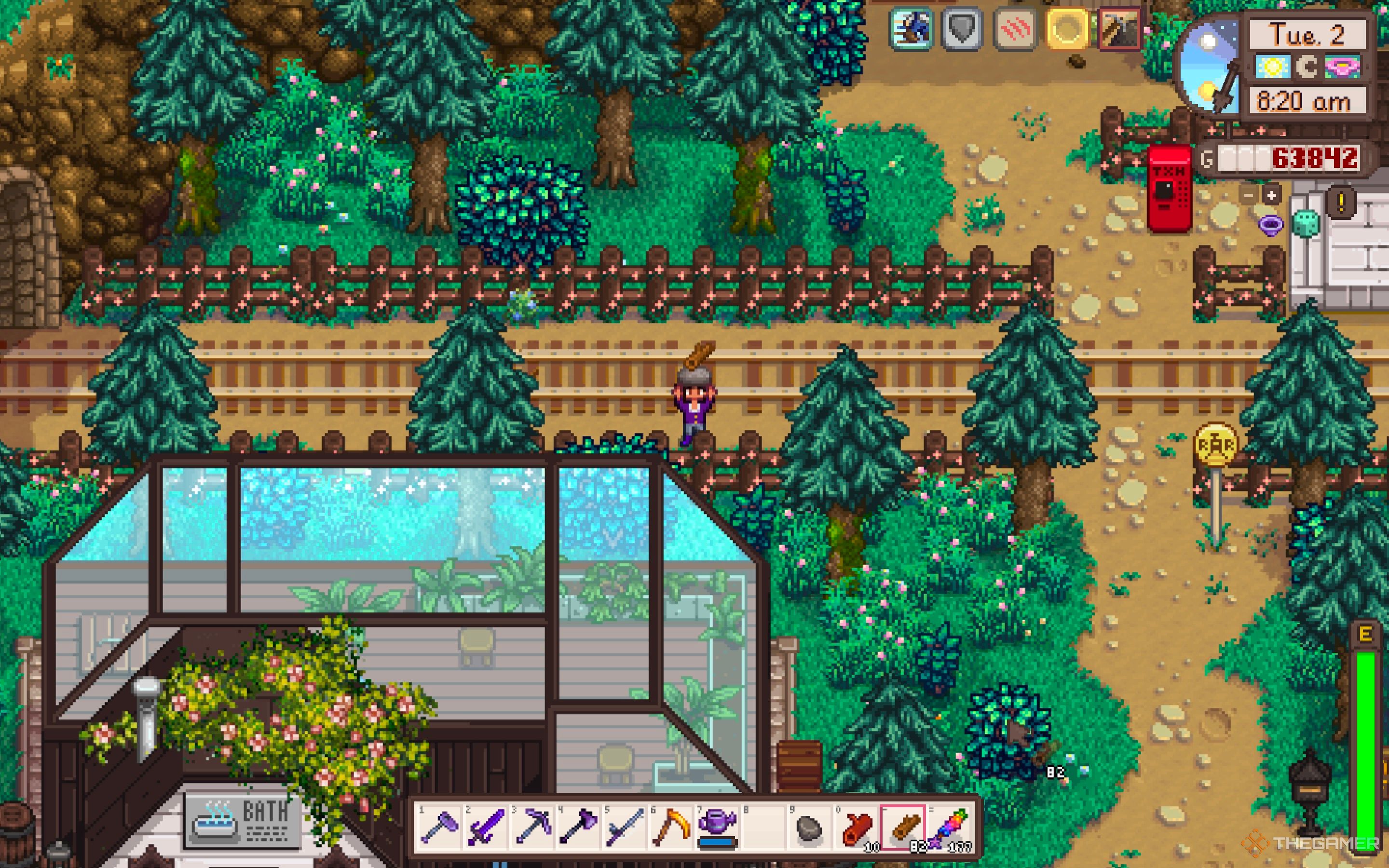 Granjero de Stardew Valley parado junto a las vías del tren, sosteniendo madera
