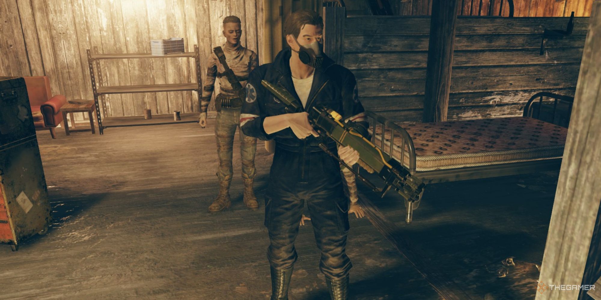 Una captura de pantalla de Fallout 76 que muestra al personaje del jugador sosteniendo un arma de energía larga en espera, con el arma apuntando hacia un lado y hacia el suelo.  Se puede ver al personaje del jugador con un mono de Responders y una máscara de gas.