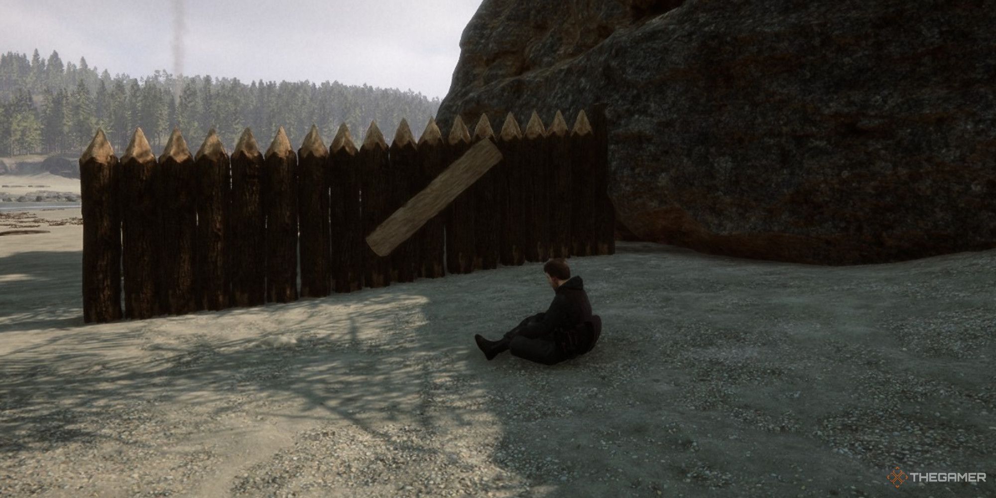 Una captura de pantalla de Sons of the Forest que muestra a Kelvin sentado frente a un muro defensivo con una puerta que se abre en la playa.